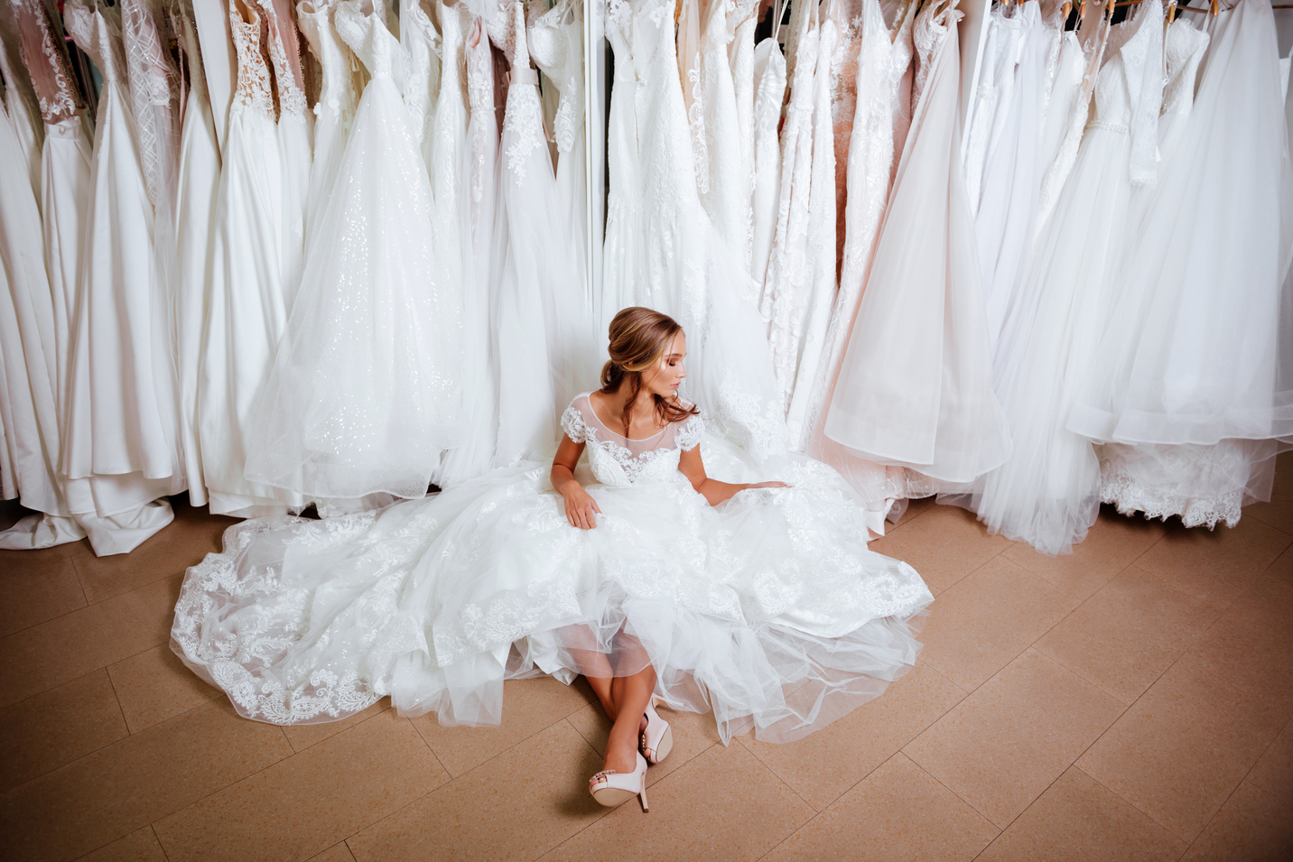 Attractive young bride is smiling while choosing wedding dress